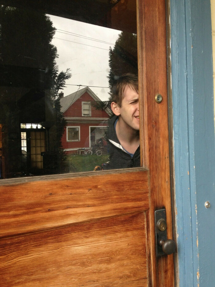 A person squinting through a narrow gap next to a wooden door, illustrating pointless things serving no purpose.