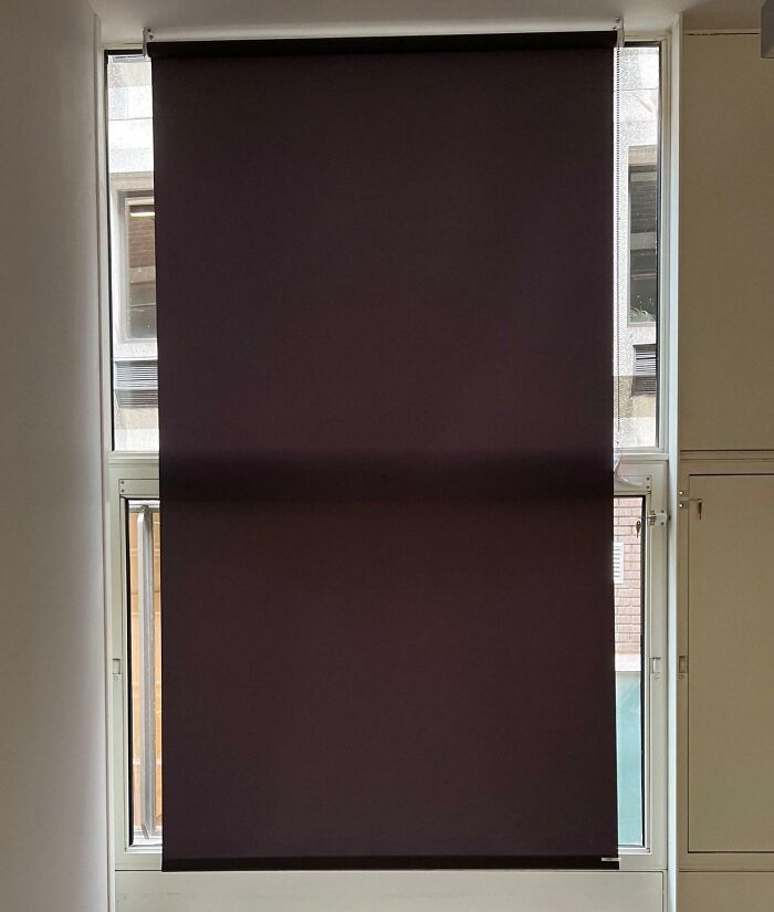 Window with a roller blind installed so poorly that it covers two different window sections unevenly, showing job failure. Window with a roller blind installed so poorly that it covers two different window sections unevenly, showing job failure.