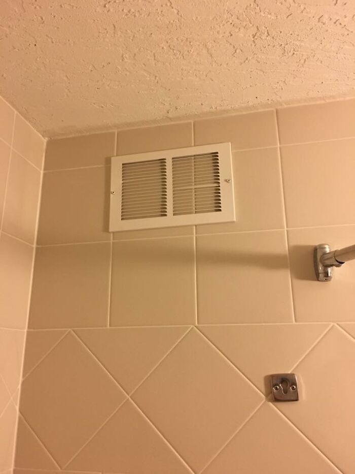 Bathroom vent positioned unusually high on tiled wall, an example of pointless things serving no purpose except being funny.