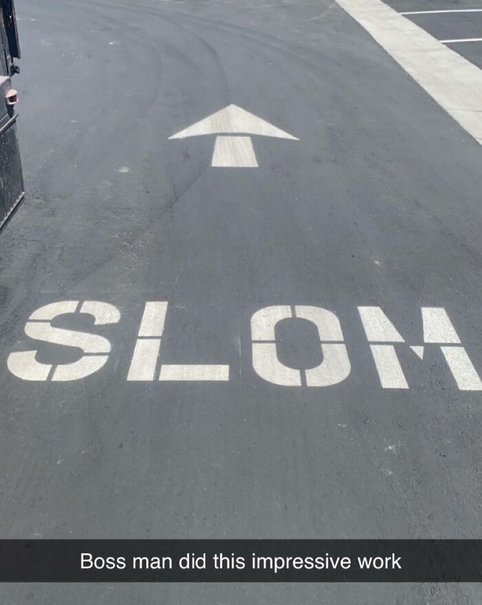 Parking lot with an arrow painted on pavement and the word slow misspelled, showing poor job e*******n.