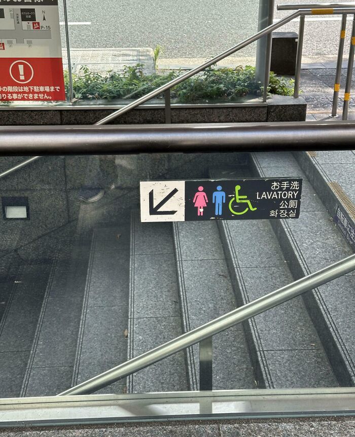 Sign directing to accessible lavatory located down a set of stairs, illustrating poor job safety in public facility design.