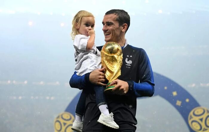 Man holding a child and a trophy, capturing a rare coincidence moment in a celebration scene.