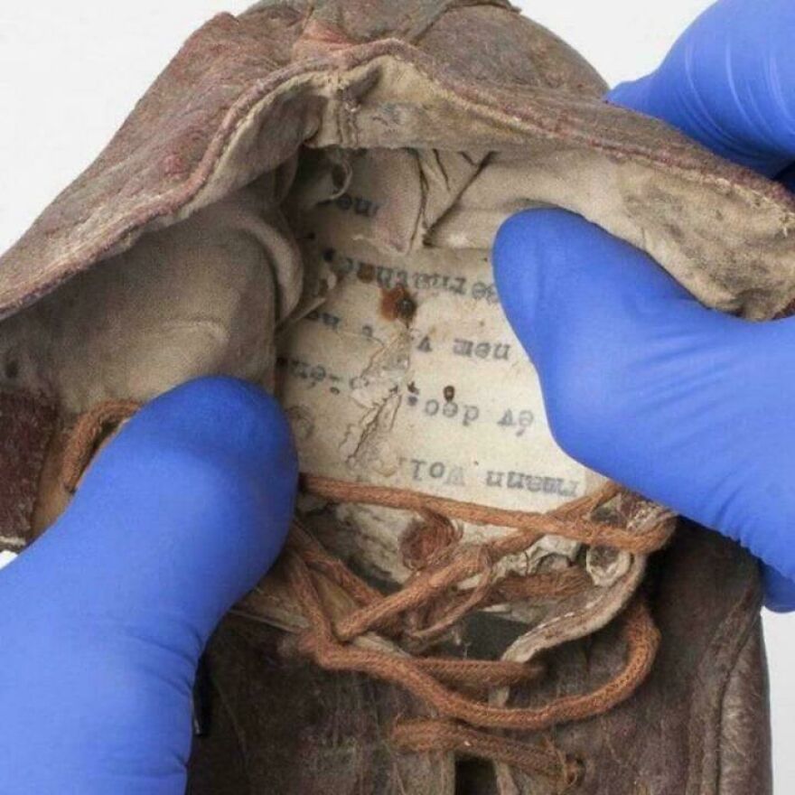 Old worn shoe being inspected with blue gloves, revealing hidden text inside, a random picture worth going down a rabbit hole for.