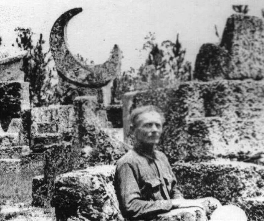 Black and white photo of a man sitting among stone structures with a crescent shape, intriguing random pictures to explore.