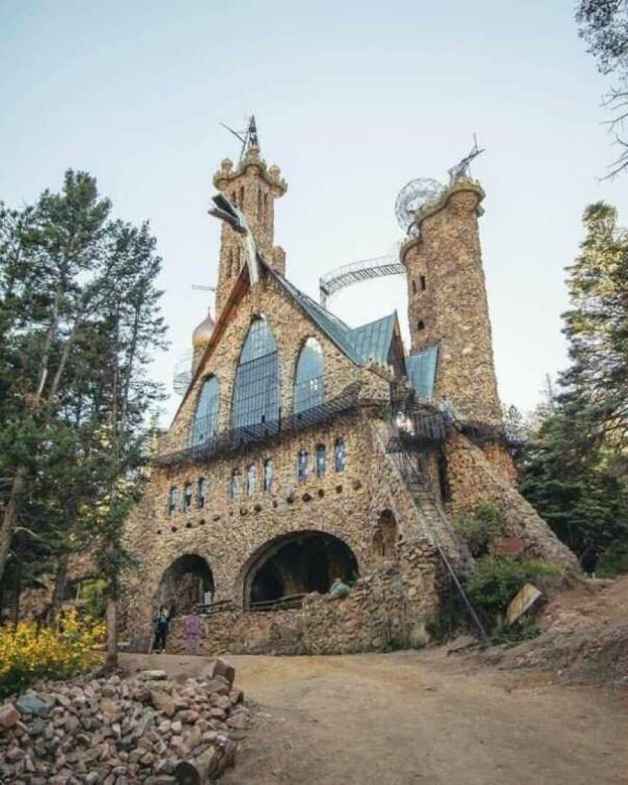 Stone castle with unique towers and arches surrounded by trees, a random picture worth going down a rabbit hole for.