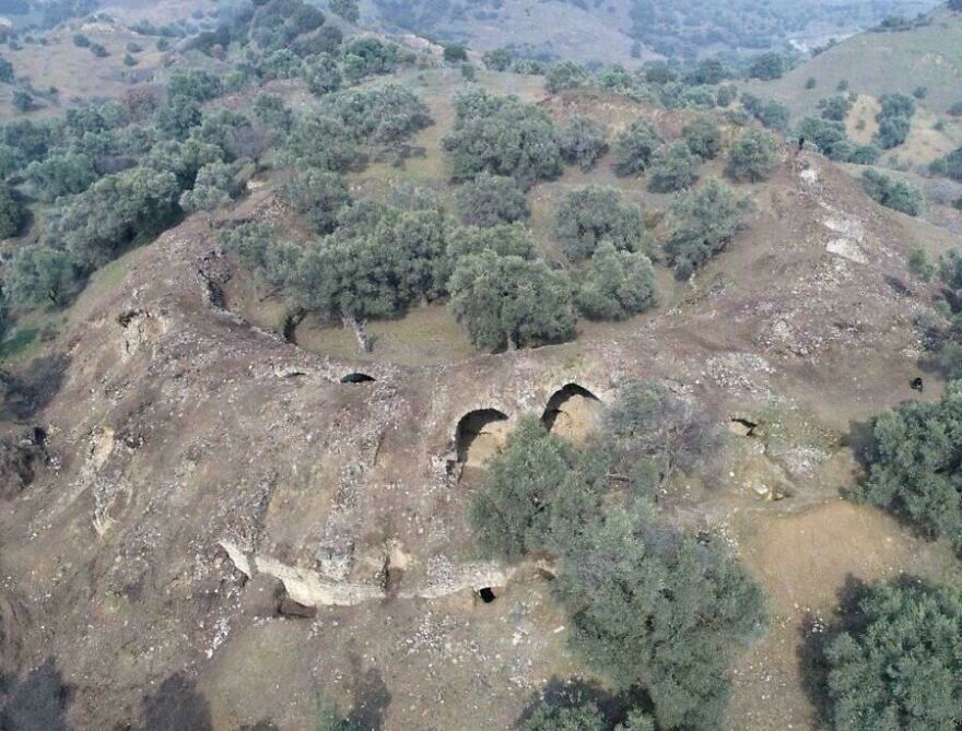 Aerial view of ancient ruins surrounded by trees in a hilly area, one of the random pictures worth exploring further.