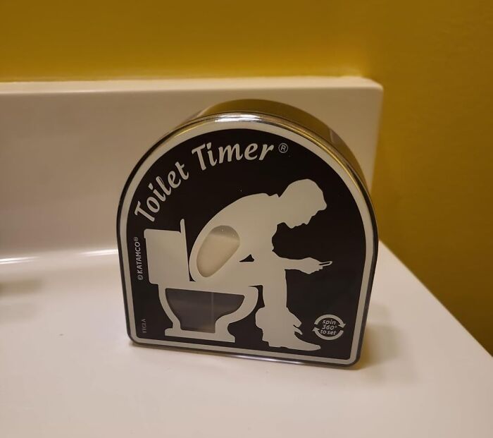 Novel gag gift toilet timer sitting on bathroom counter, perfect for friends who find scented candles humorous.
