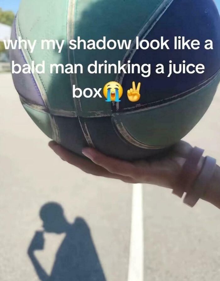Shadow cast by hand holding basketball creates a confusing illusion of a bald man drinking from a juice box, brain teaser photo.