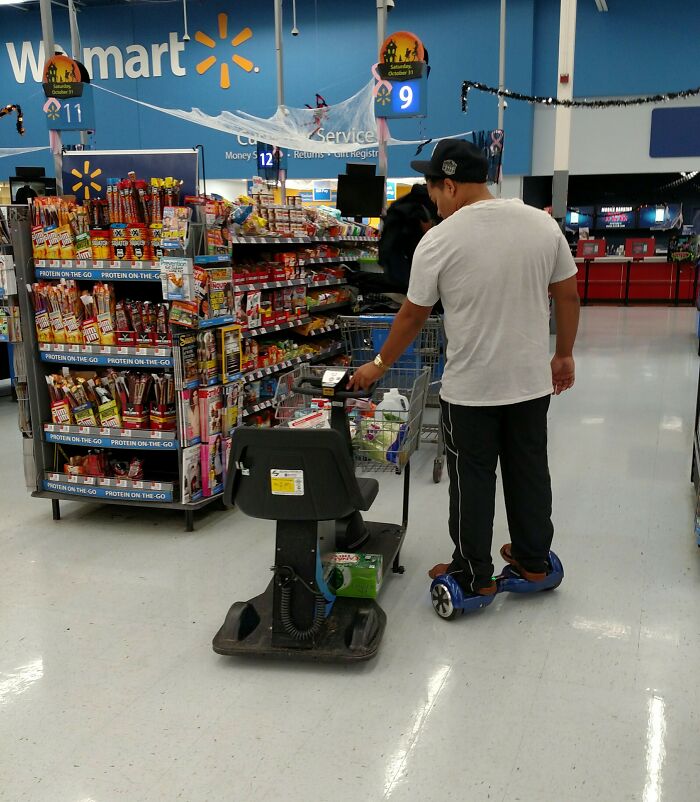 Man on hoverboard pushing electric cart inside Walmart store with various snacks and products on shelves nearby