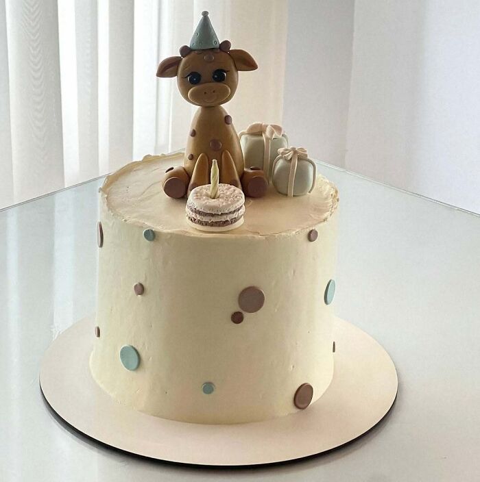 Minimalist cake decorated with a giraffe figure, small presents, and colorful polka dots, showcasing masterfully crafted cakes.
