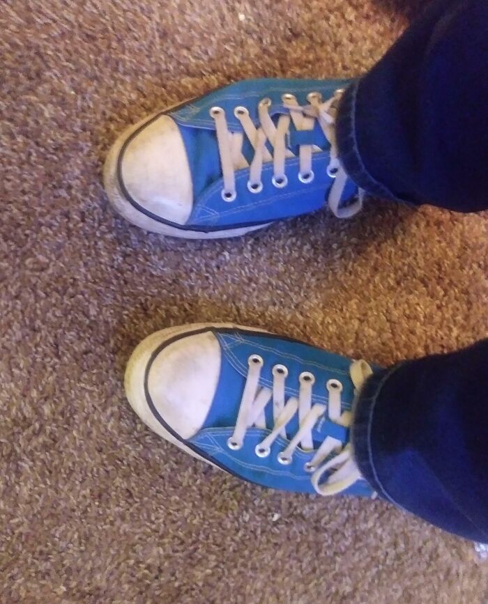 Worn blue sneakers on carpeted floor symbolizing people taking a leap of faith and making life decisions.