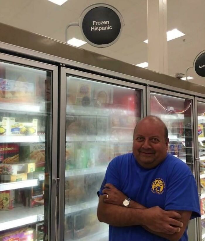 Man smiling and standing with arms crossed near frozen food section in store, capturing heartwarming photos moment.