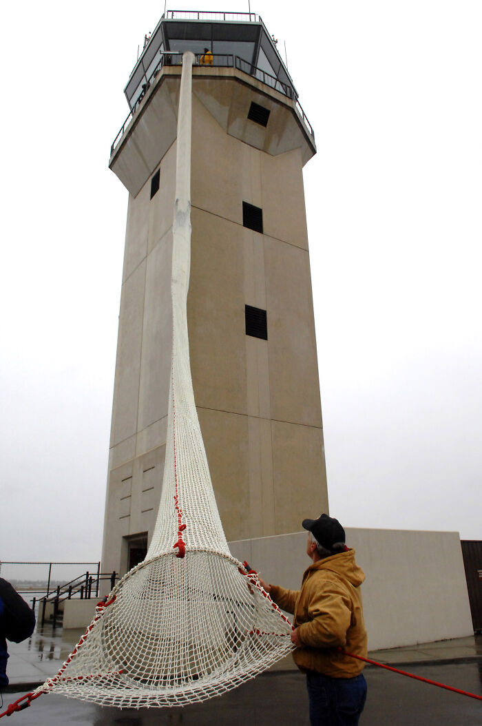 Air traffic controller using a safety net below a control tower, showcasing different jobs that make a 9-to-5 more bearable.