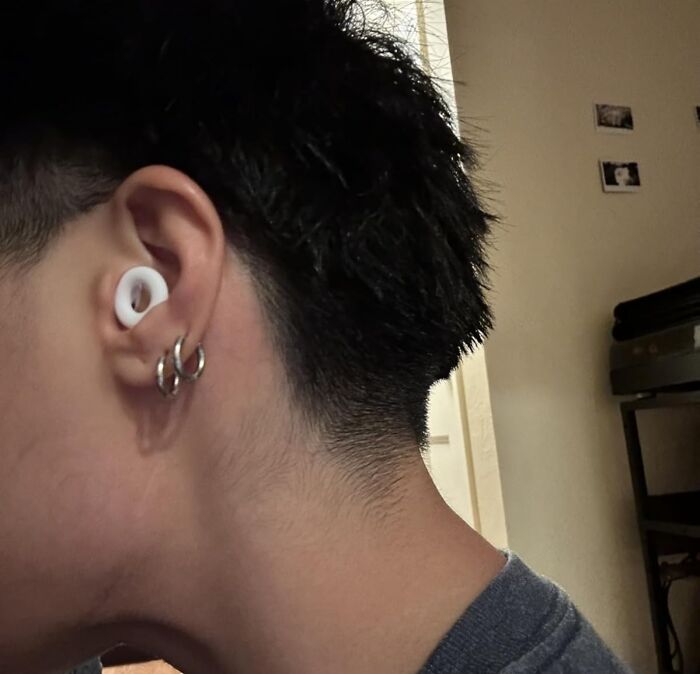 Close-up of a person wearing modern wireless earbuds and silver hoop earrings, showcasing a unique gift idea for mother-in-law.