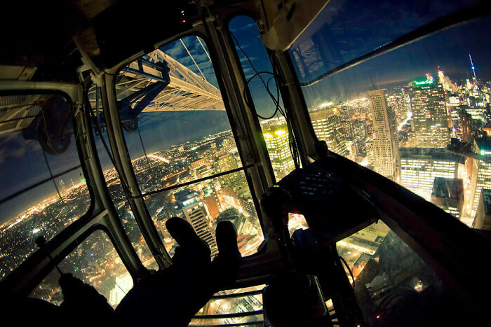View from inside a crane operator’s cabin high above a cityscape at night showcasing unique job perspectives.