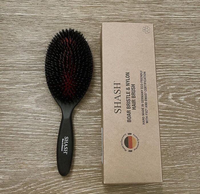 Boar bristle and nylon hair brush by Shash next to its eco-friendly packaging on a wooden surface, ideal gift idea.