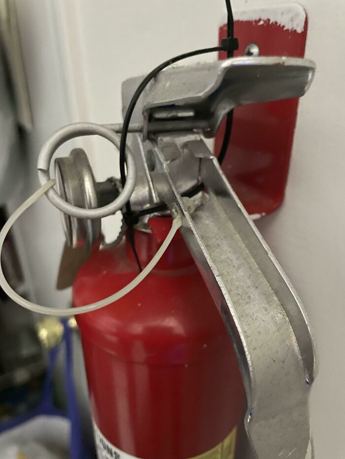 Close-up of a fire extinguisher with a damaged safety pin, illustrating rental nightmares where landlords cut corners and got exposed.