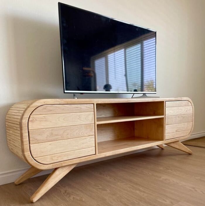 Modern woodworker project featuring a sleek carved wooden TV stand with rounded edges and open shelves.