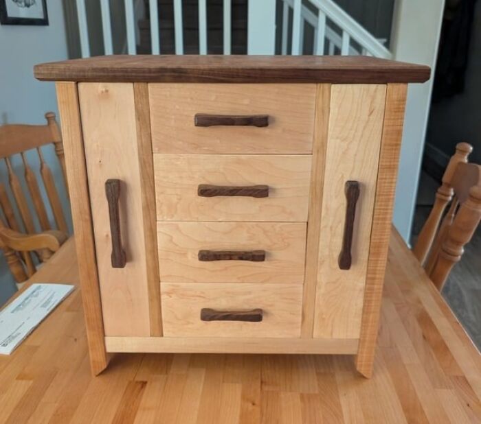 Handcrafted wooden cabinet with carved drawer and door handles showcasing woodworking skill and fine craftsmanship.