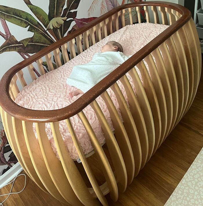 Handcrafted wooden baby crib showcasing woodworking project with smooth curved slats and polished finish.