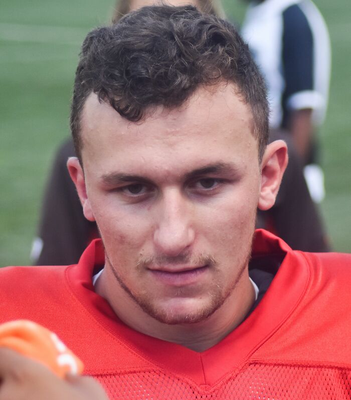 Johnny Manziel wearing red football uniform during a game, showcasing highlights of his sports career.