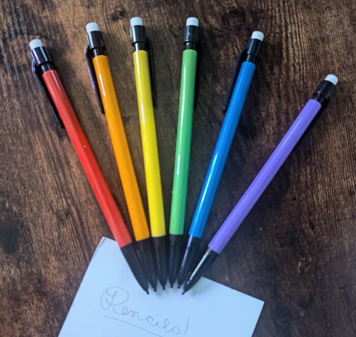 Colorful rainbow mechanical pencils arranged on wooden surface with a note, a perfect gift for a teacher with patience and caffeine love