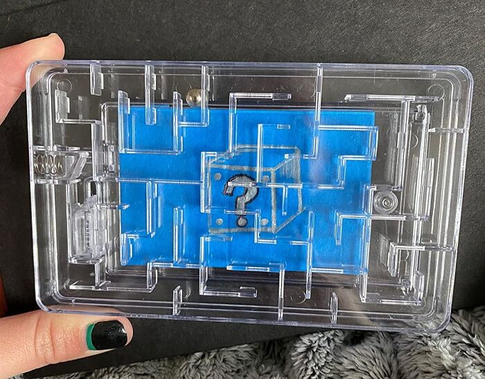 Hand holding a clear plastic maze puzzle toy, symbolizing gifts for the teacher with patience and caffeine a*******n.