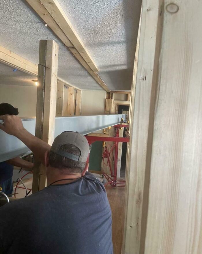 Worker ignoring safety protocol while handling heavy steel beam in a tight construction space without proper support.