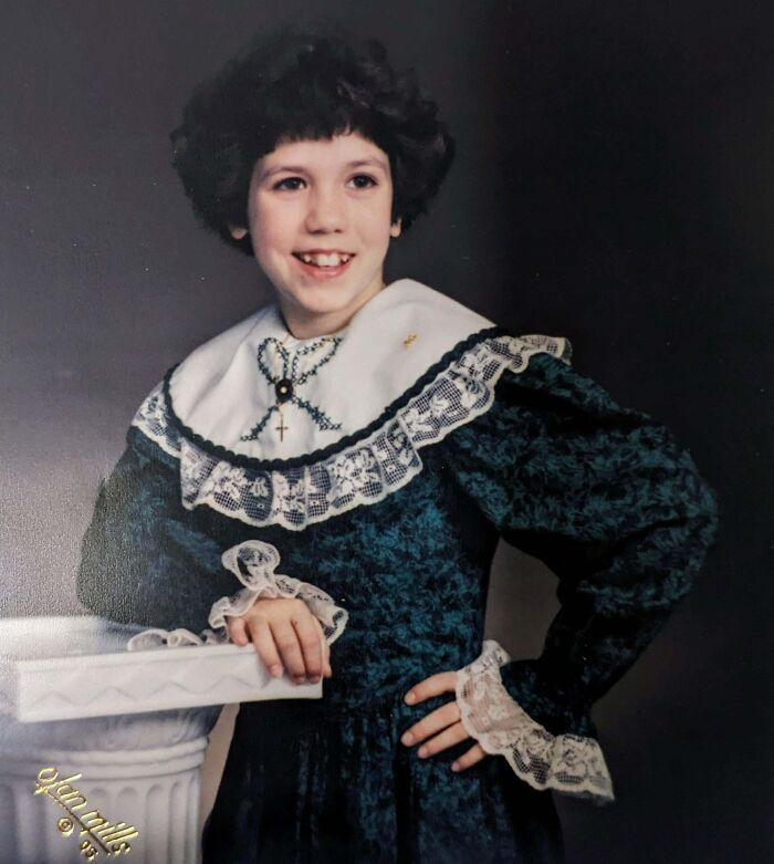 Child in vintage lace dress posing awkwardly for a hilariously awkward childhood photo from the collection.