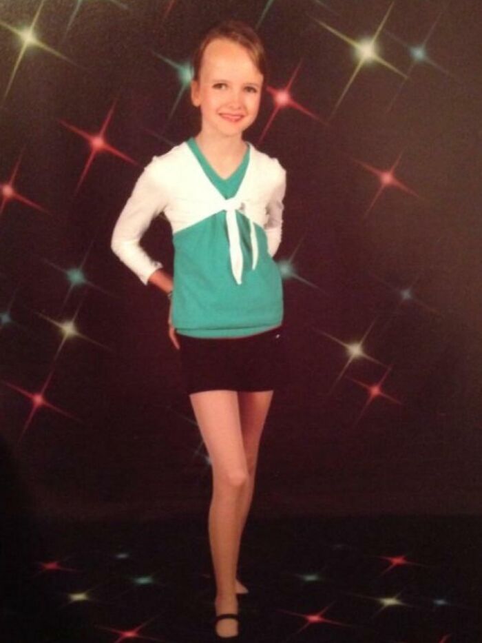 Young girl striking a confident pose in a retro outfit against a colorful sparkling backdrop, awkward childhood photo vibe.