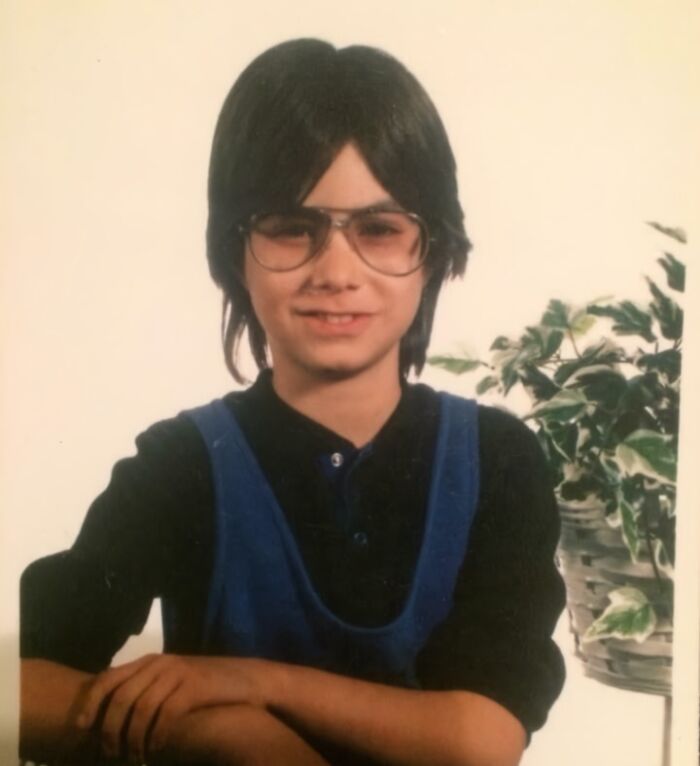 Vintage childhood photo of a boy wearing glasses and a blue vest, capturing hilariously awkward childhood moments.