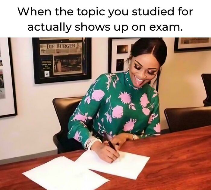 Student happily writing at a desk, illustrating college memes about students running on hope and energy drinks during exams.