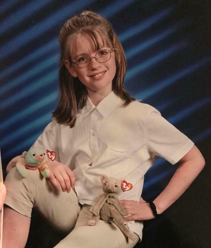 Childhood photo of a girl with glasses posing with Beanie Babies, capturing a hilariously awkward moment.