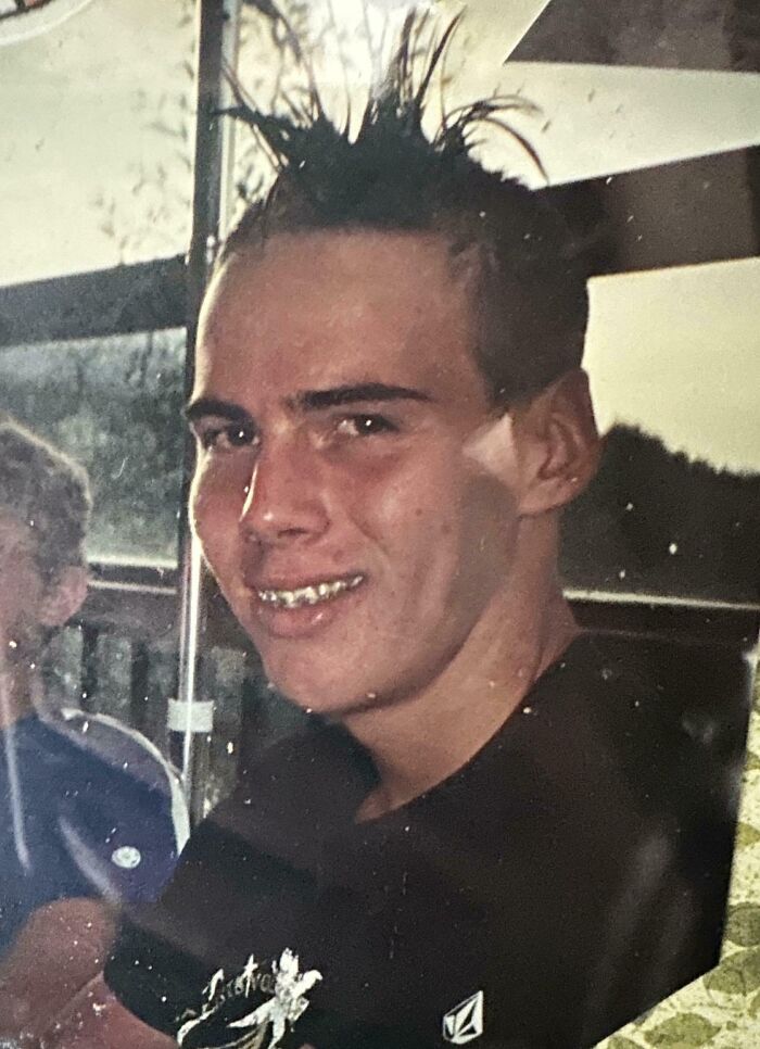 Teen boy with spiked hair and braces smiling in vintage awkward childhood photo from hilarious childhood moments collection.