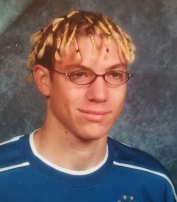 Teen boy with awkward hairstyle and glasses posing for a hilariously awkward childhood photo in a school portrait.