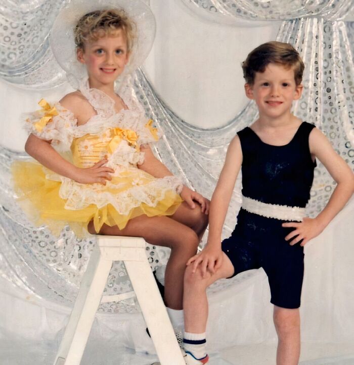 Two children in vintage dance costumes posing against a sparkly backdrop in an awkward childhood photo moment.