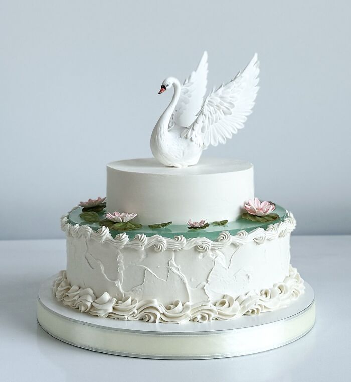 Elegant cake with a detailed swan topper and floral decorations, showcasing masterfully crafted cake creativity and design.