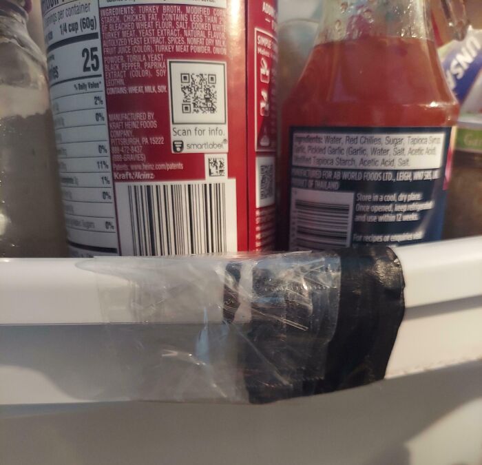 Refrigerator door with c*****d hinge taped together, showcasing a rental nightmare where landlords cut corners and got exposed.