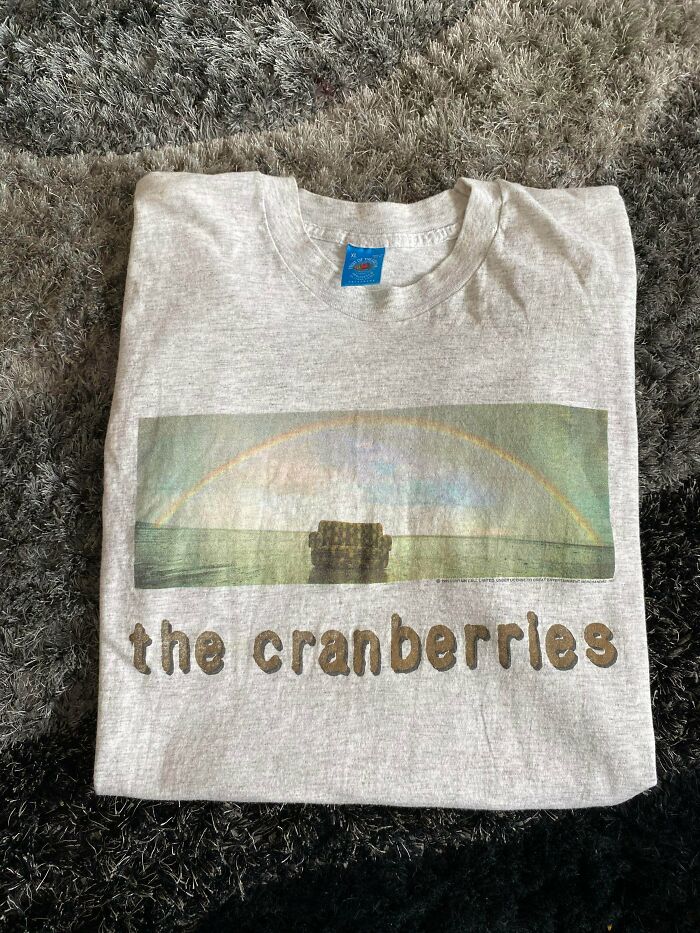 Folded vintage The Cranberries band T-shirt on a carpet, showcasing a cool secondhand store surprise find.
