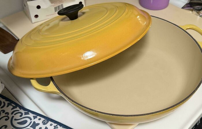 Yellow enameled cast iron pot with lid slightly open, a cool secondhand store find on a kitchen stove.