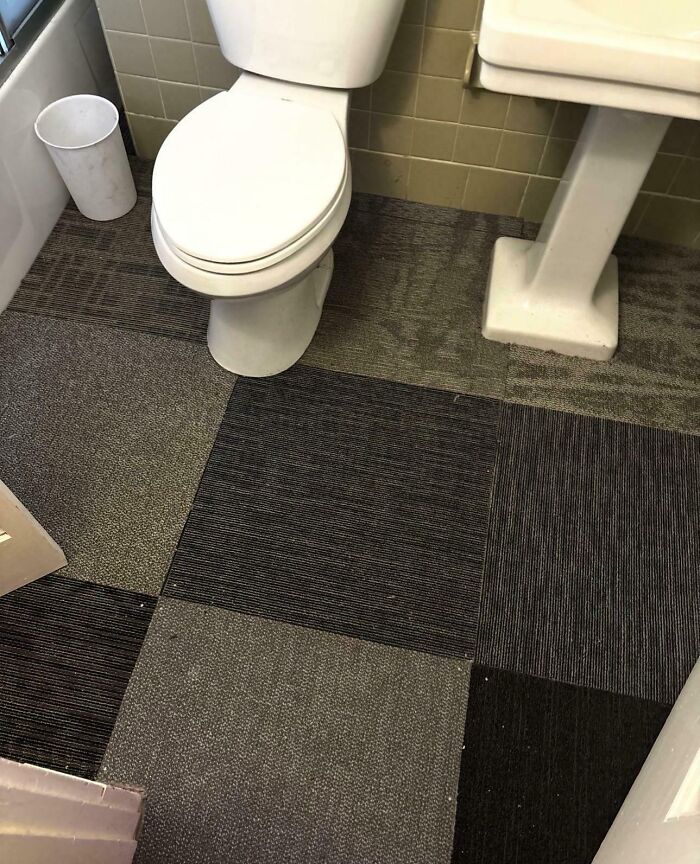Bathroom with toilet and sink, featuring carpet tiles on the floor, illustrating rental nightmares from landlords cutting corners.