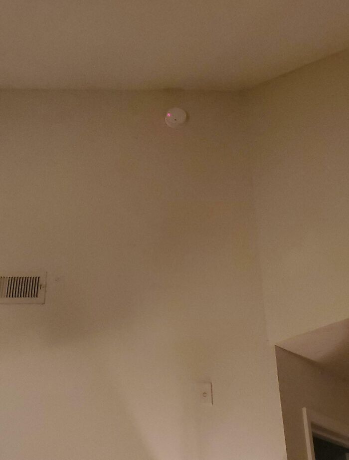 Smoke detector installed too high in corner of rental unit ceiling, illustrating rental nightmares and landlord corner-cutting exposed.