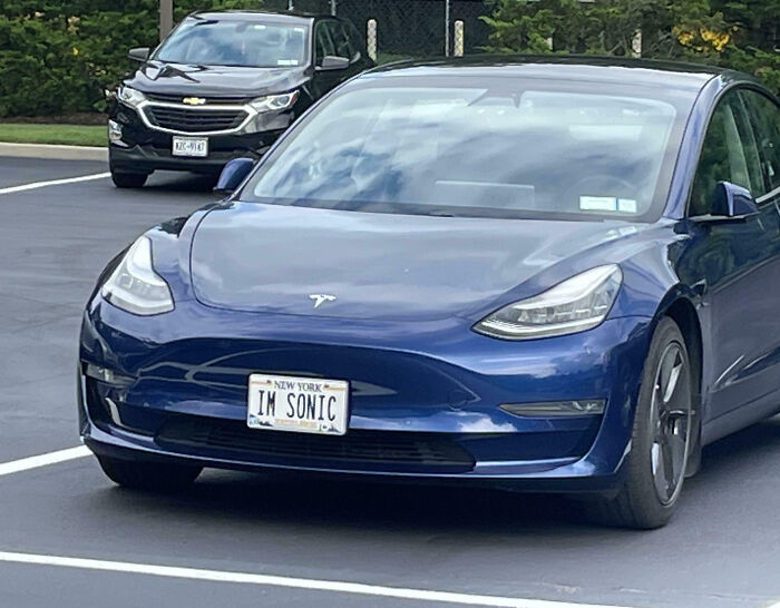 Blue Tesla with a personalized license plate reading IM SONIC parked in a lot, showcasing funny personalized license plates.