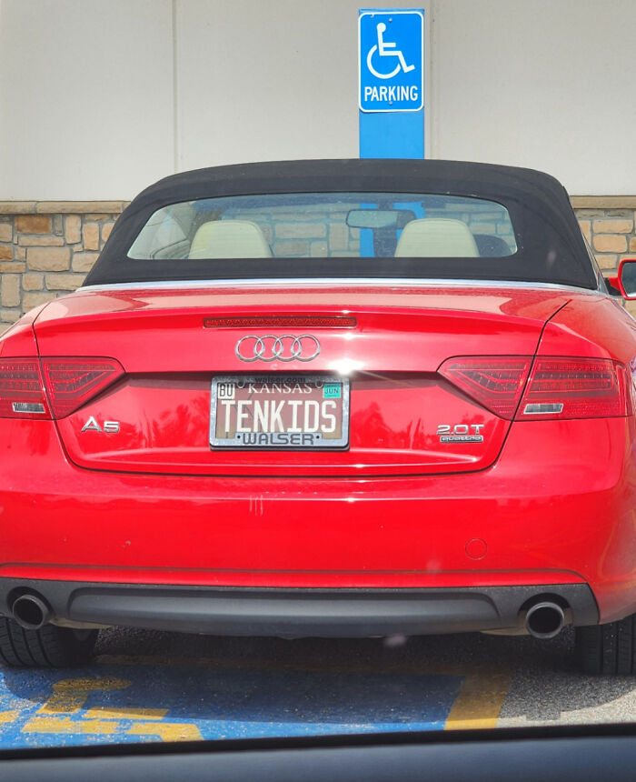 Red Audi A5 convertible with a personalized license plate reading TENKIDS in a handicapped parking spot.