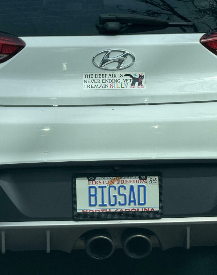 White Hyundai car with a personalized license plate reading BIGSAD and a humorous bumper sticker about remaining silly.