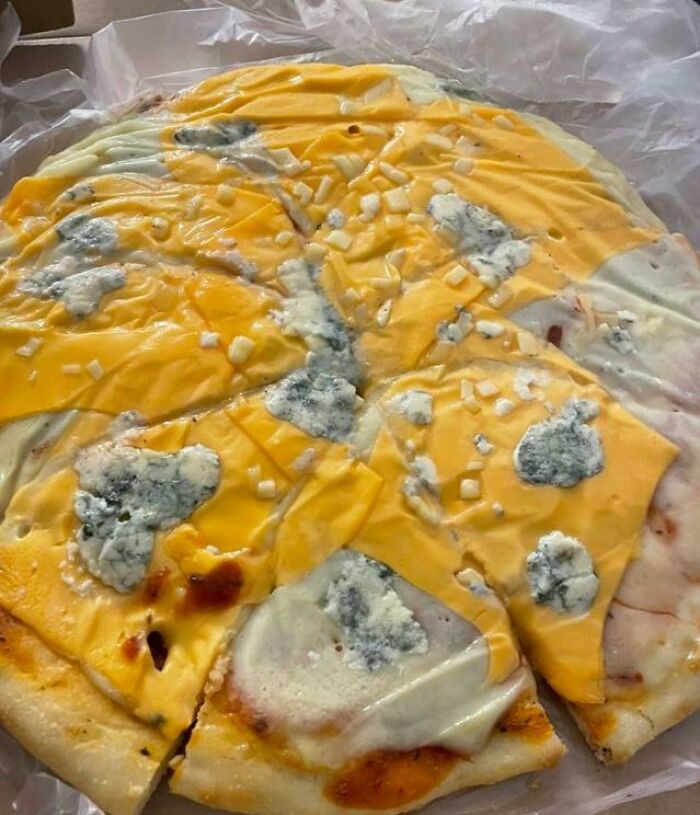 Pizza covered with mold and melted cheese on wax paper, an example of outrageous meals that look nothing like menu photos.
