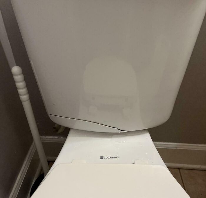 Toilet tank with a visible crack at the bottom, illustrating rental nightmares where landlords cut corners and caused damage.