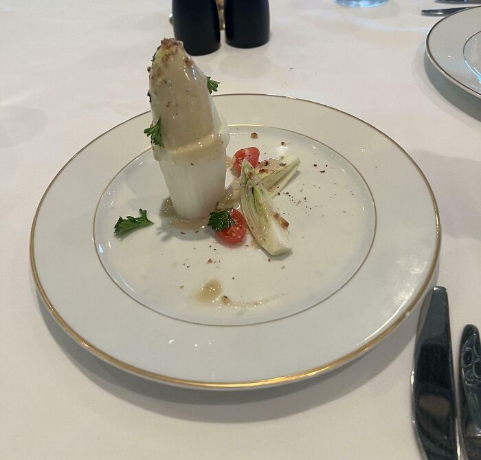 Small portion of an unusual plated meal with sauce, cherry tomato, and herbs, illustrating outrageous meals vs menu photos.