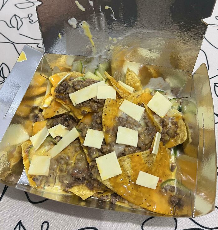 Box of nachos with uneven cheese slices and ground beef, an example of outrageous meals that look nothing like menu photos.