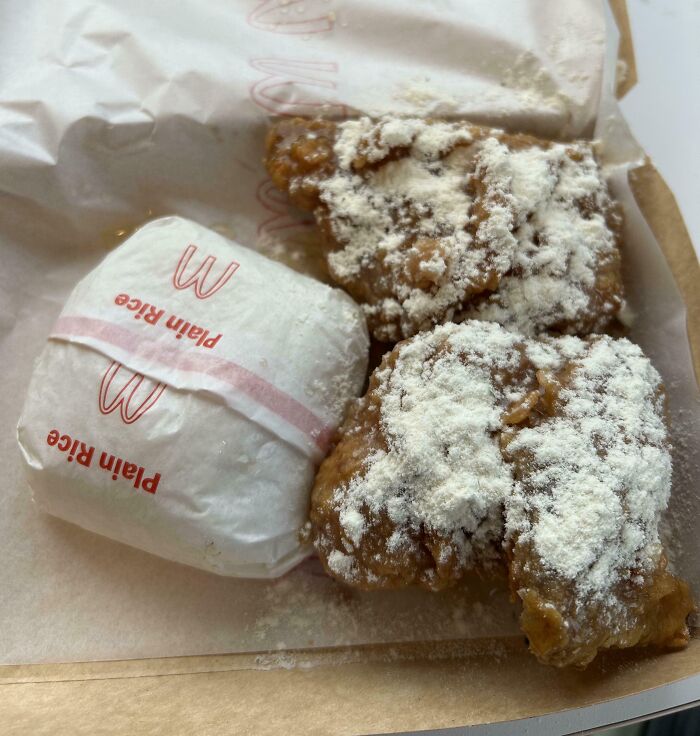 Fried chicken pieces covered in white powder next to a small wrapped plain rice portion, an outrageous meal with misleading appearance.